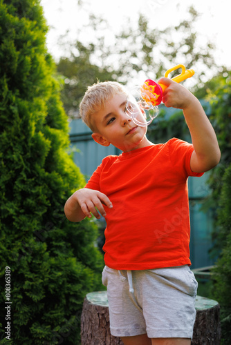 Boy child, bubbles and backyard garden with mockup space in summer sunshine by trees for playing game. male kid, blowing bubble and outdoor with soap, games and rainbow in nature, park and mock up