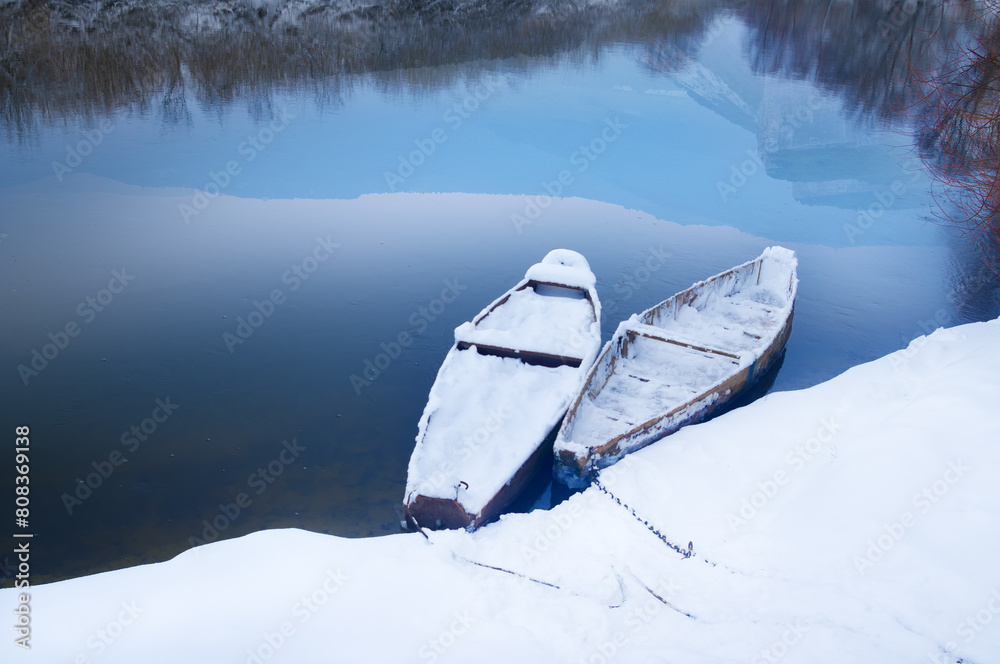 Φωτογραφία Two spoons near the bank of a winter river in which the peaks of the surrounding mountains are reflected