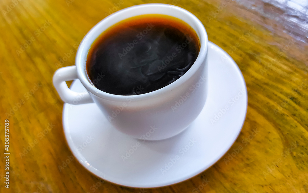 White cup of black Americano coffee on a wooden table. White cup of black Americano coffee on a wooden table.