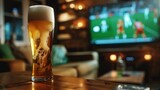 glass of beer on a small wooden table in a house with a TV in the background watching a soccer game in high resolution and high quality. drinks concept