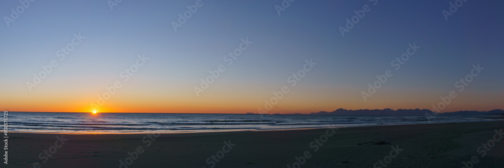 Panoramic view of sandy sea beach with Amalfi Coast in the background during evening twilight after sunset, Paestum, Campania, Italy
