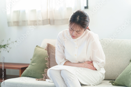 お腹を押さえる女性　体調不良　腹痛 photo