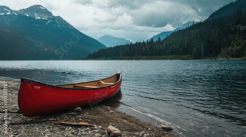 A red canoe is docked on the shore of a picturesque lake with majestic mountains towering in the background  surrounded by a serene natural landscape under a cloudy sky AIG50