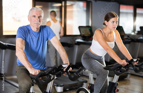 Elderly athletic man in sportswear training on exercise bike in gym © JackF