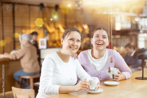 Two happy women drinking coffee and talking in quiet cafe © JackF