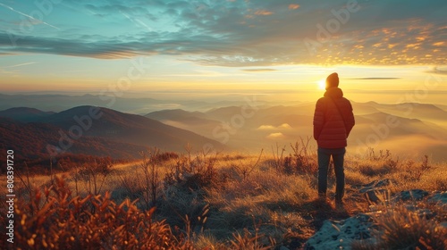 Solitary figure admires autumn sunrise over mountain 