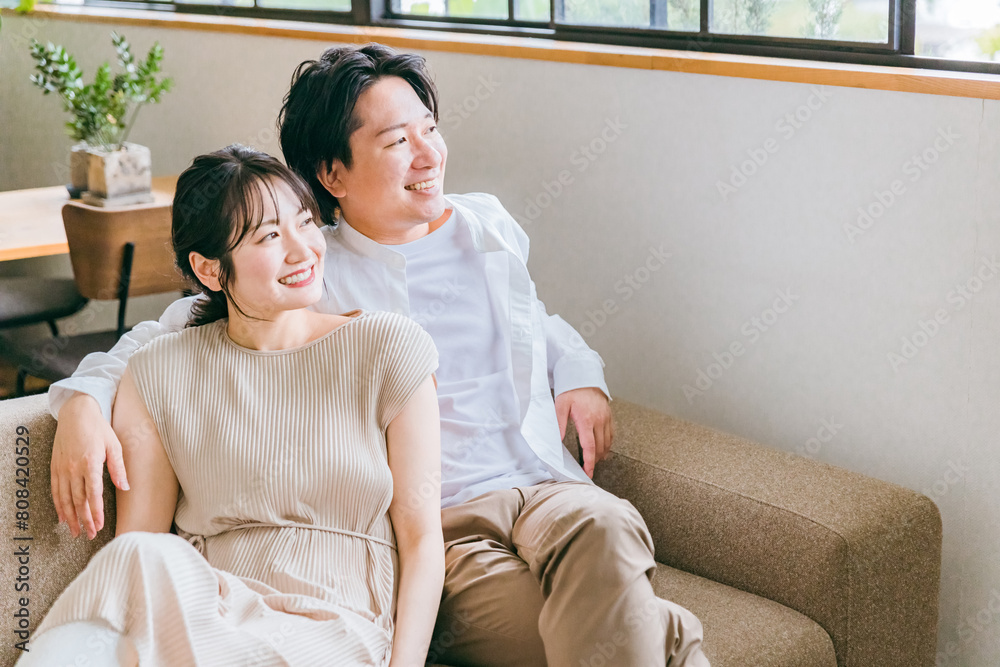 Φωτογραφία 家のリビングでソファーに座って外を眺める若いアジア人夫婦