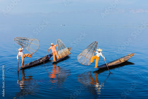 Myanmar travel attraction landmark - Traditional Burmese fishermen balancing with fishing net on boats at Inle lake in Myanmar famous for their distinctive one legged rowing style © Dmitry Rukhlenko