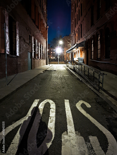 Dark side street at night with light shining in the distance in New York City NYC photo