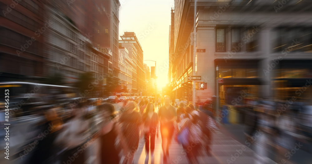 Crowds of people walking across the busy intersection at 23rd Street and 5th Avenue in New York City with the light of sunset background and motion blur