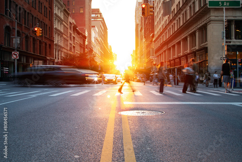 Crowds of people and cars in motion through the busy intersection on 5th Avenue and 23rd Street in New York City with sunlight in background photo