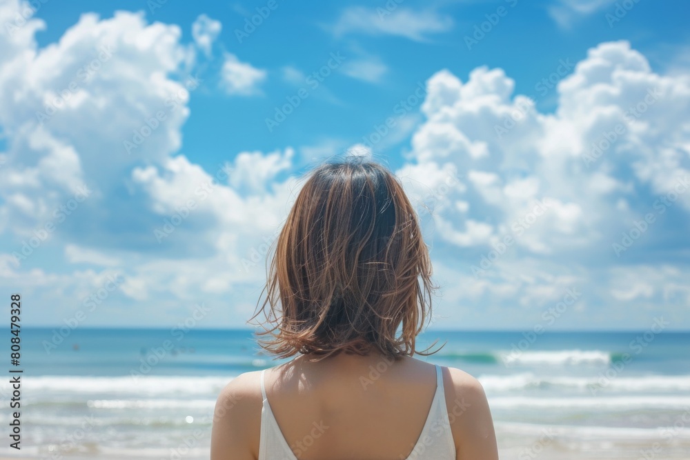 海を見ている日本人女性の後ろ姿（ビーチ・青空・旅行・休暇）