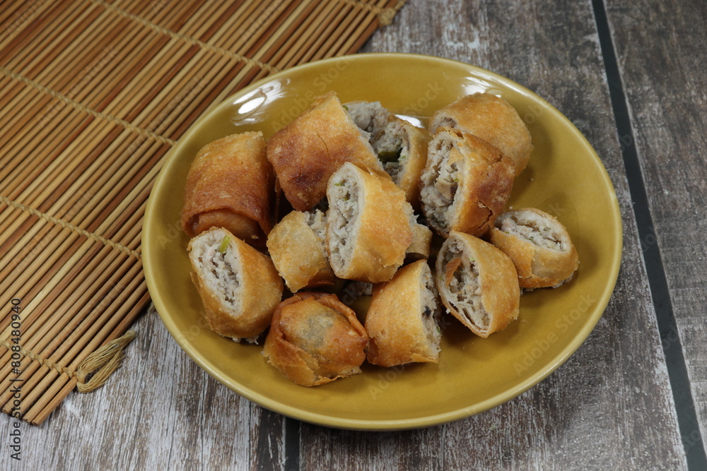 Cutting deep fried spring roll serving on the plate. Famous appetizer dim sum menu in Chinese restaurant. Cutting deep fried spring roll serving on the plate. Famous appetizer dim sum menu in Chinese restaurant.