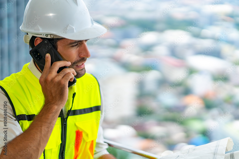 Male civil engineer contractor in safety helmet and jacket standing on construction site building speaking on mobile phone discussion real estate development working plan with architect manager. Male civil engineer contractor in safety helmet and jacket standing on construction site building speaking on mobile phone discussion real estate development working plan with architect manager.