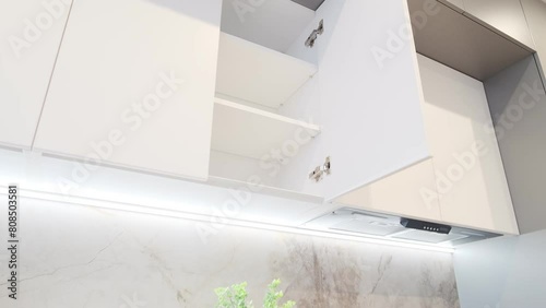 Open kitchen cabinet door. Modern classic white kitchen interior with furniture and appliances. Camera zoom
