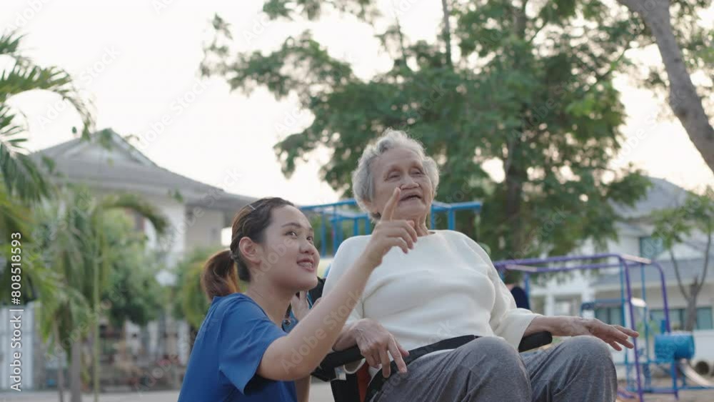 Young nurse and elderly asian senior woman on wheelchair, Asian careful caregiver and patient, Nurse gives a pep talk to an elderly female patient in the garden in the evening. Health insurance. Young nurse and elderly asian senior woman on wheelchair, Asian careful caregiver and patient, Nurse gives a pep talk to an elderly female patient in the garden in the evening. Health insurance.