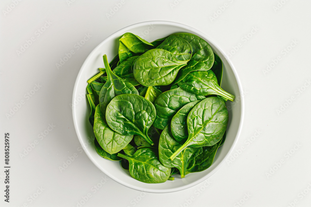 a bowl of spinach leaves on a white surface a bowl of spinach leaves on a white surface