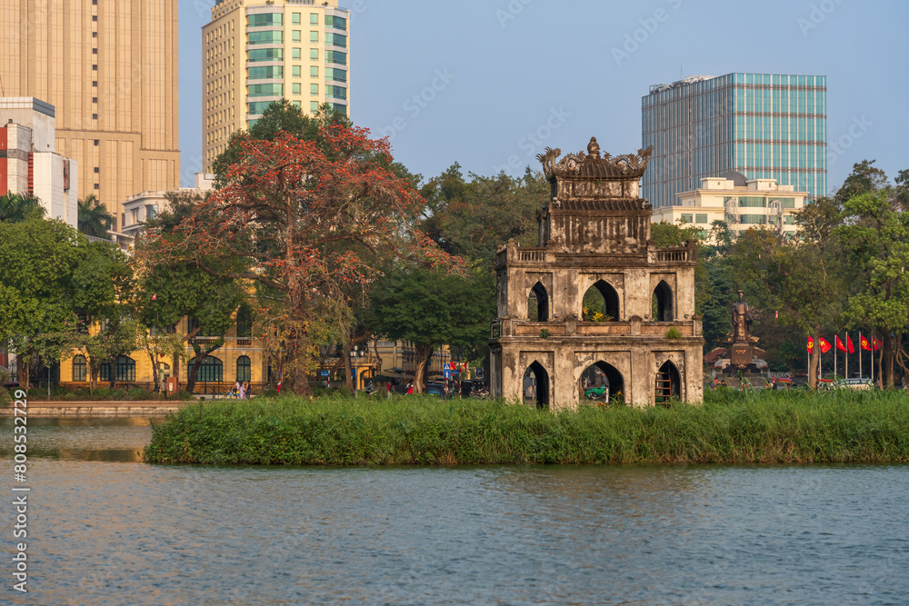 Turtle Tower (Thap Rua) in Hoan Kiem lake (Sword lake, Ho Guom) in Hanoi, Vietnam. Blooming bombax ceiba tree on background.