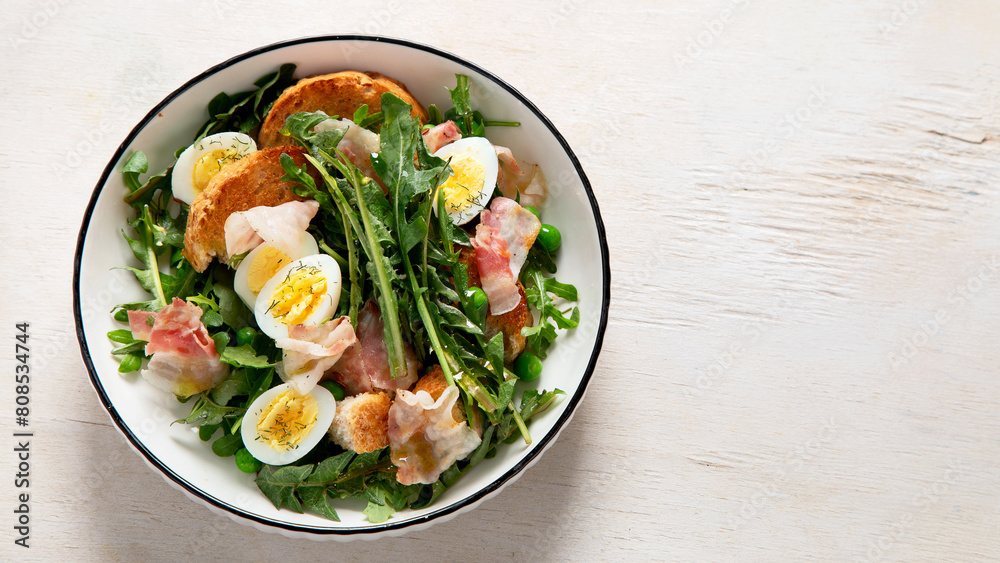 Summer fresh salad from dandelion leaves, eggs, bacon and with bread on light background Summer fresh salad from dandelion leaves, eggs, bacon and with bread on light background