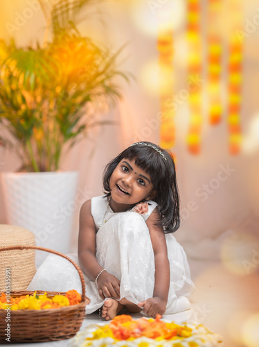 Happy Onam background, Cute little girl wearing traditional dress and making Onam pookalam with flowers © sarath