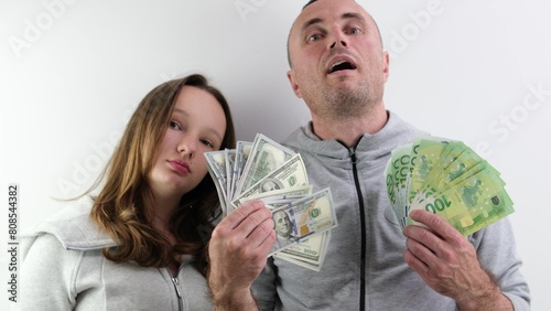 father and daughter a lot of money in their hands joy success dollars euro 100 dollar bill wave money like a fan look into the frame make faces confidence success big win purchase. gift