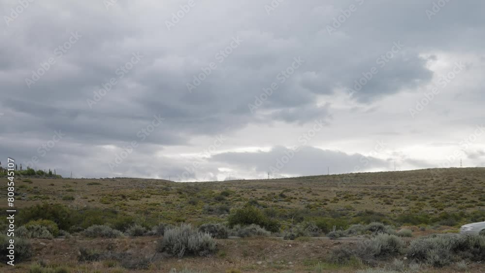 White car driving across desert landscape with cloudy sky White car driving across desert landscape with cloudy sky