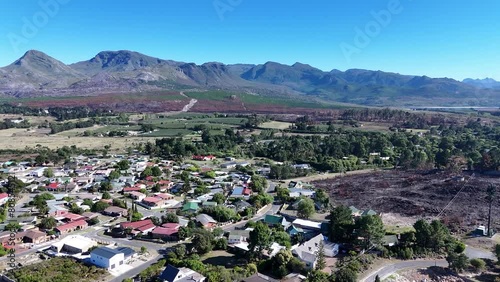 Drone shot of a Grabouw suburb in Cape Town South Africa. Experience the breathtaking beauty of Grabouw, Cape Town, as a drone soars above, showcasing the landscape and towering mountains. photo