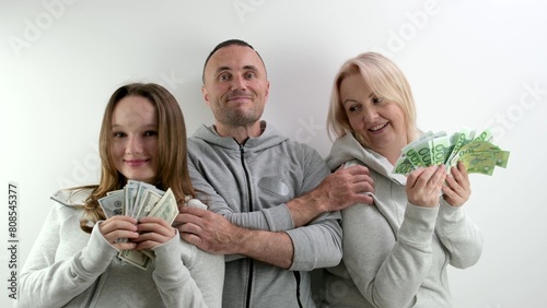 happy rich family dollars and euros in the hands of mom daughters dad father hugs them smiling happy waving money like fan on a white background a lot of money luck travel in games. kissing relatives