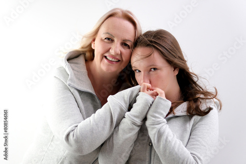 love of daughter and mother hugging kisses tenderness girl kisses her mother's hands mother hugs kisses her daughter on the cheek two women on a light background. a lot of tenderness and joy of love