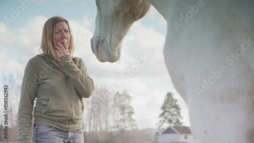 Woman lets feelings go and interacts with white horse during horse therapy photo