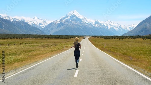 Girl standing by renowned State Highway 80, adjacent to Lake Pukaki, with a view of Mount Cook