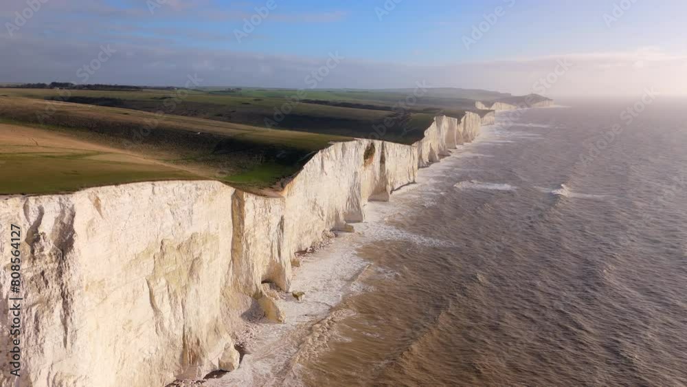 Towering white cliffs alongside the sea glow under the golden light of sunset, creating a breathtaking natural landscape symbolizing endurance and beauty. Seven Sisters, Brighton, United Kingdom 