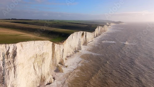 Towering white cliffs alongside the sea glow under the golden light of sunset, creating a breathtaking natural landscape symbolizing endurance and beauty. Seven Sisters, Brighton, United Kingdom 