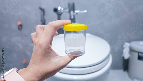 medical specimen collection bottle , urine test jar on the flush toilet photo