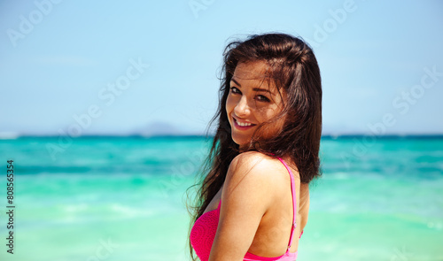 Beautiful happy healthy woman with tanned body in pink swimsuit smiling in blue amazing island sea with brown long hair. Relaxing holidays. Sun summer seaside portrait