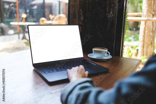 Mockup image of a woman working on laptop computer with blank white desktop screen in cafe