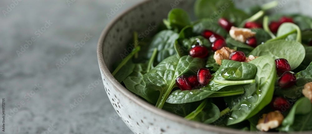 Obraz premium A closeup highlights the textures and colors of a salad with spinach, walnuts, and pomegranate seeds