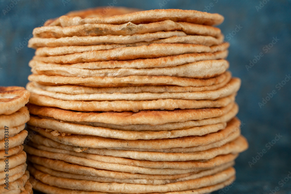 Flatbread lavash, chapati, naan, heap of tortilla on a blue background Homemade flatbread stacked. Flatbread lavash, chapati, naan, heap of tortilla on a blue background Homemade flatbread stacked.