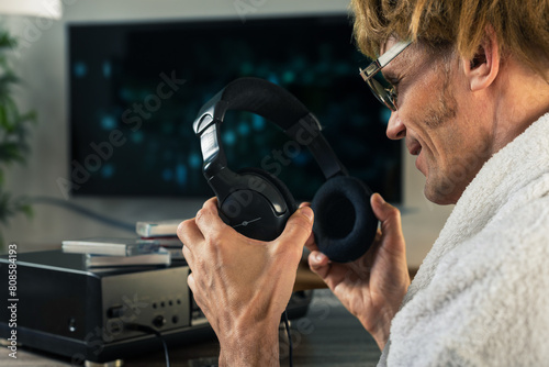 Male music meloman wearing headphones to listen to music on retro cassette boombox. In a room filled with memories, man enjoys music from a tape recorder photo
