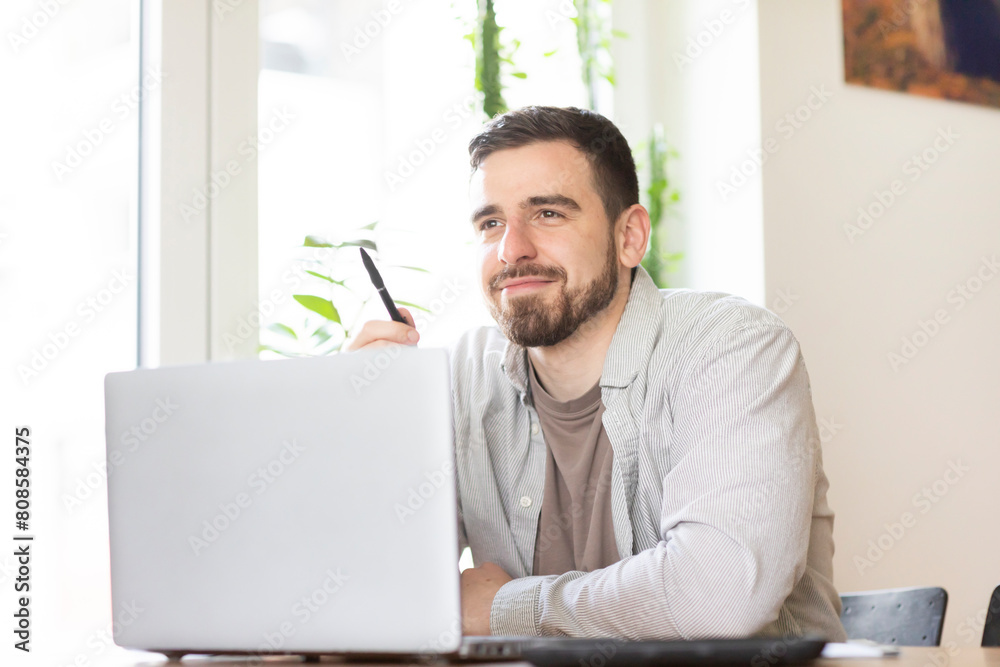 man with beard working in home office with pencil and laptop man with beard working in home office with pencil and laptop