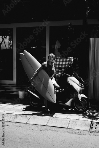 Portrait young happy stylish woman with a surfboard on a motorbike.