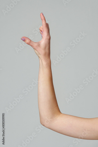 Female hand sign against gray background in studio