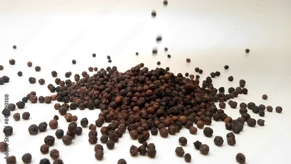 Black pepper falling on clean white background in the center frame, close up, herbs and spices Black pepper falling on clean white background in the center frame, close up, herbs and spices