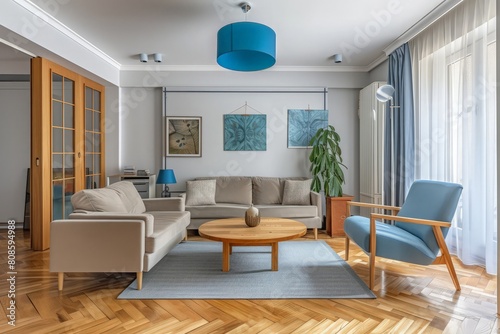 Modern living room setup with classic parquet floor. Furnished with light gray sofa  blue arm chair with wooden frame  modern blue ceiling lamp  wooden coffee table and gray carpet.