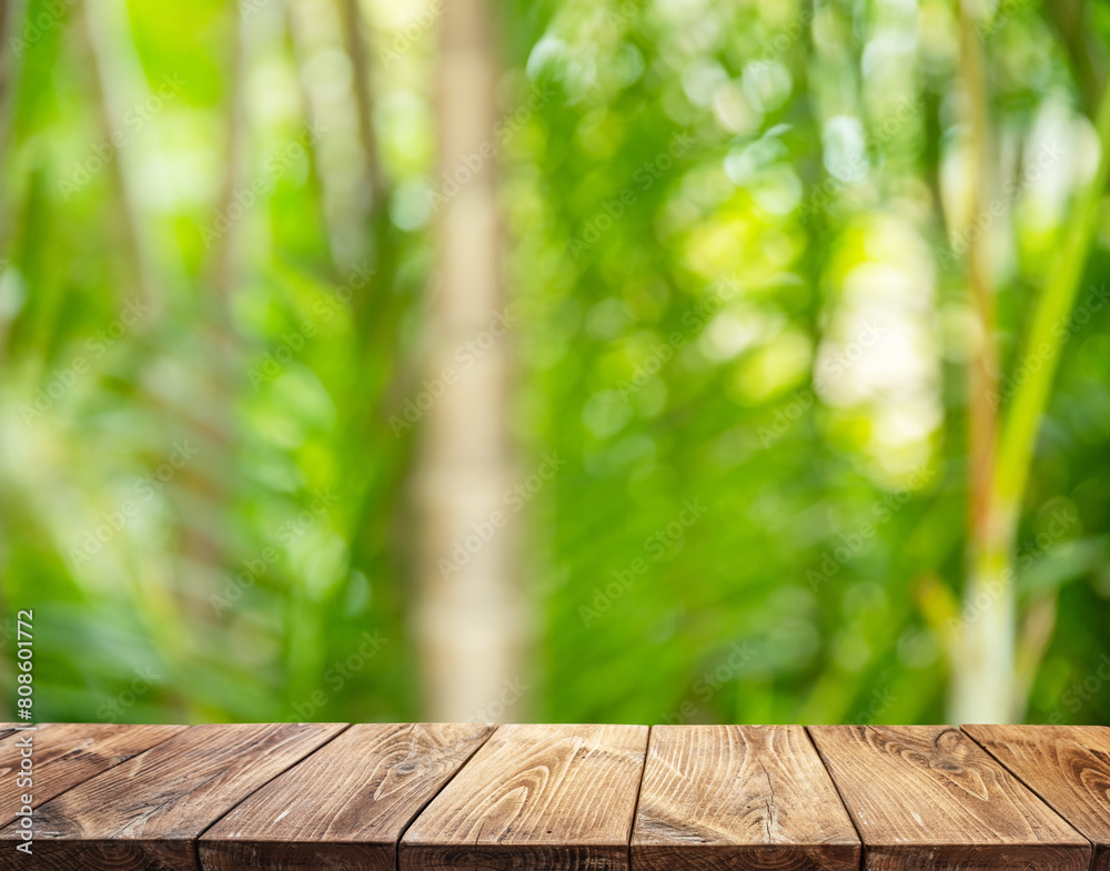 Empty wooden board or table top and blurred green bamboo culms. Place for your product display. Empty wooden board or table top and blurred green bamboo culms. Place for your product display.