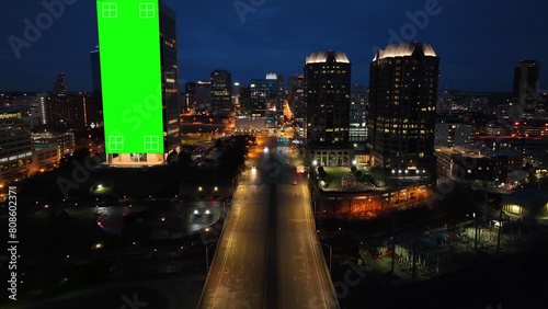 American city at night with green screen animated on skyscrapers for advertisement. Aerial of highway with lights at dusk photo