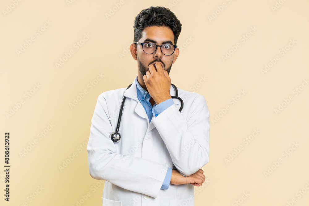 Φωτογραφία Upset scared frightened Indian doctor cardiologist man biting nails, feeling worried nervous about serious troubles, stress, anxiety disorder, panic attack, guilty