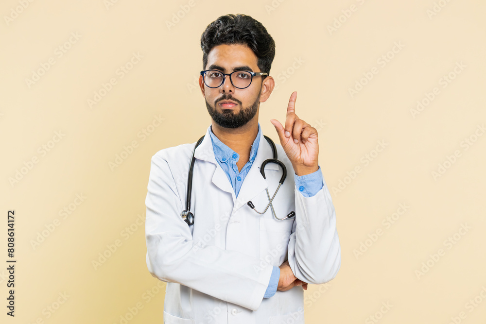 Displeased upset Indian young doctor cardiologist man reacting to unpleasant awful idea, dissatisfied with bad work, wave hand, shake head No dismiss bad idea proposal. Arabian guy on beige background Displeased upset Indian young doctor cardiologist man reacting to unpleasant awful idea, dissatisfied with bad work, wave hand, shake head No dismiss bad idea proposal. Arabian guy on beige background