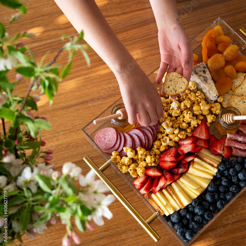 Hands reaching for crackers from a delicious charcuterie board