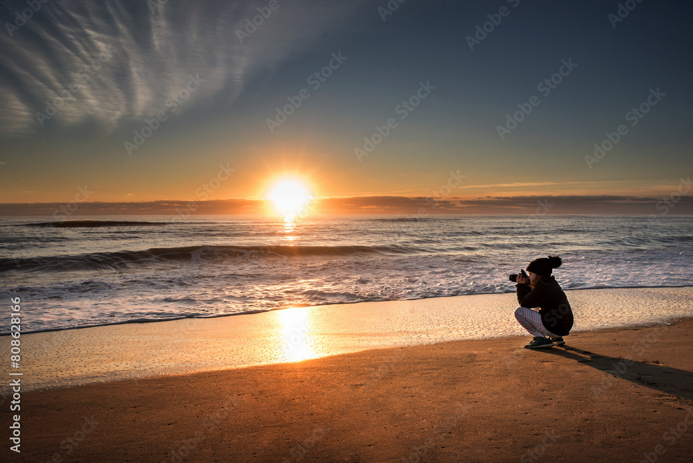 Young girl taking pictures on beautiful beach at sunrise Young girl taking pictures on beautiful beach at sunrise